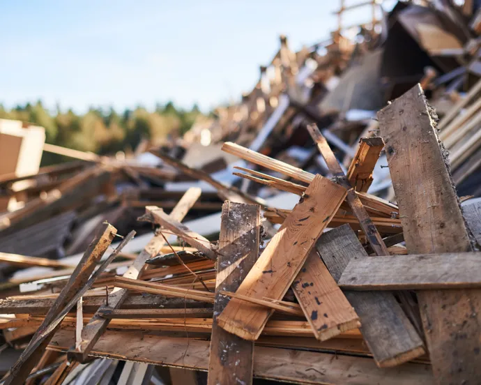 En hög med trä som ligger bredvid en skog.