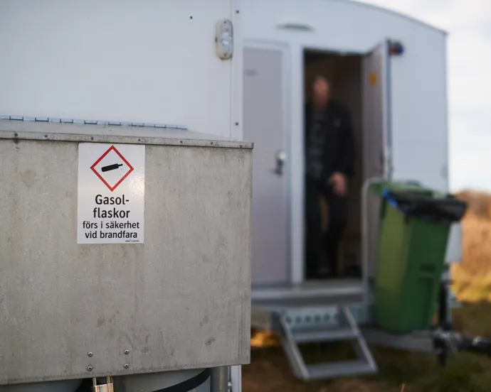 En man som står i dörröppningen till en portabel toalett.