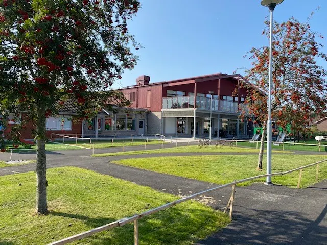 Ängsholmens röda förskola med gröna gräsmattor runt om.