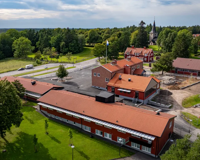 En flygbild av en röd skolbyggnad omgiven av träd.