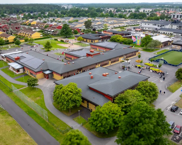 En flygbild av en skola med bilar parkerade på parkeringsplatsen.