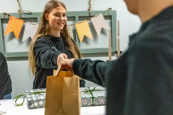 Elev på anpassad gymnasieskola som lämnar över en vara till kund